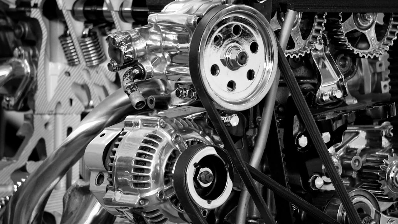 Close-up of a shiny car engine showing polished metal parts and gears in black and white.